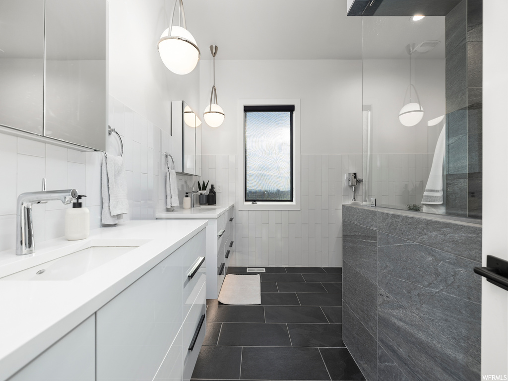 Bathroom with tasteful backsplash, tile floors, tile walls, and vanity