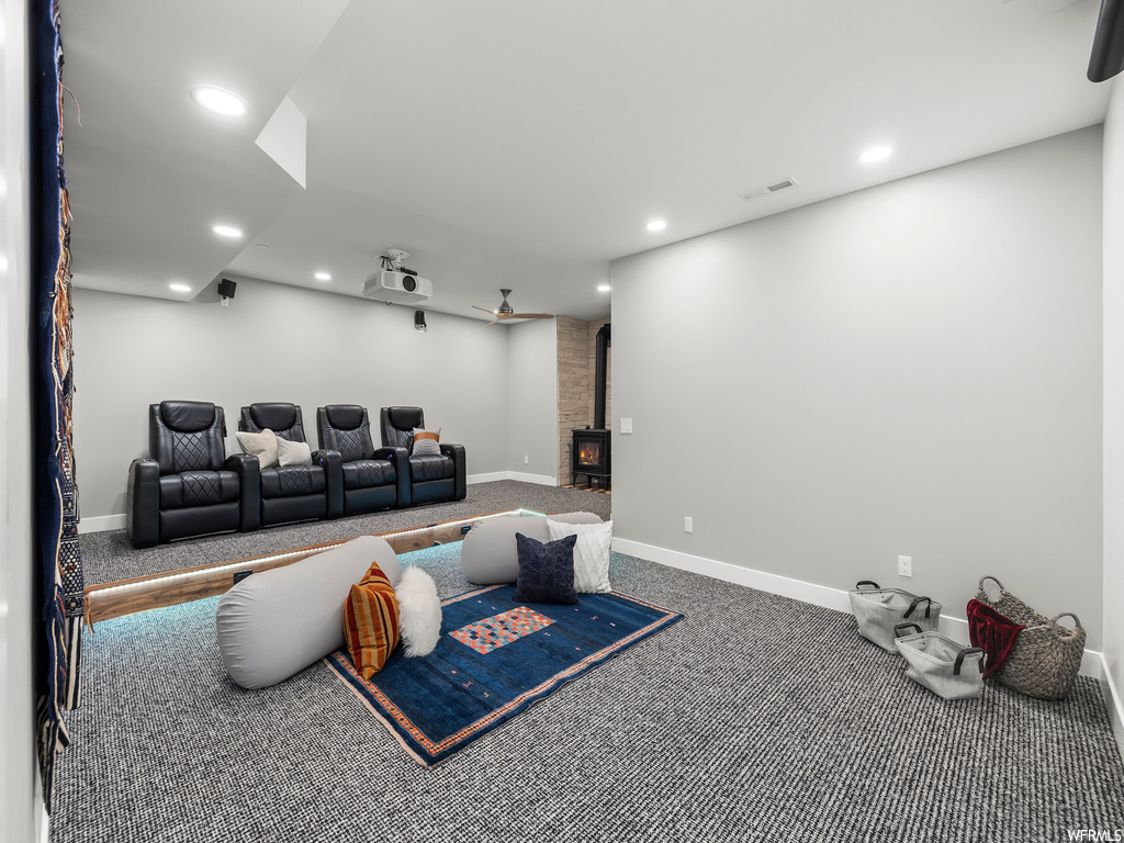 Cinema room with dark carpet and a wood stove