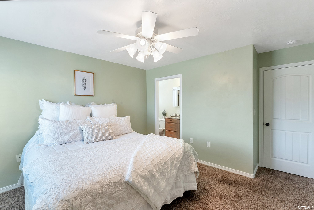 Bedroom with dark carpet, connected bathroom, and ceiling fan