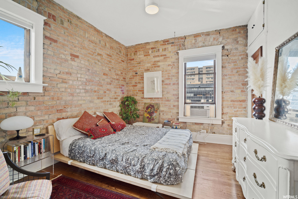 Bedroom with hardwood / wood-style flooring and brick wall