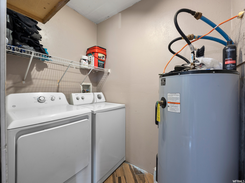 Laundry room featuring electric water heater, washing machine and clothes dryer, wood-type flooring, and washer hookup