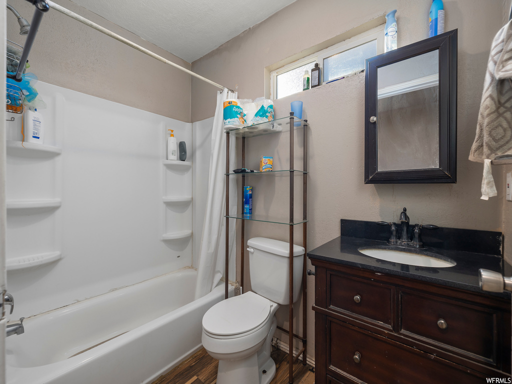 Full bathroom featuring shower / bath combination with curtain, vanity, toilet, and hardwood / wood-style floors