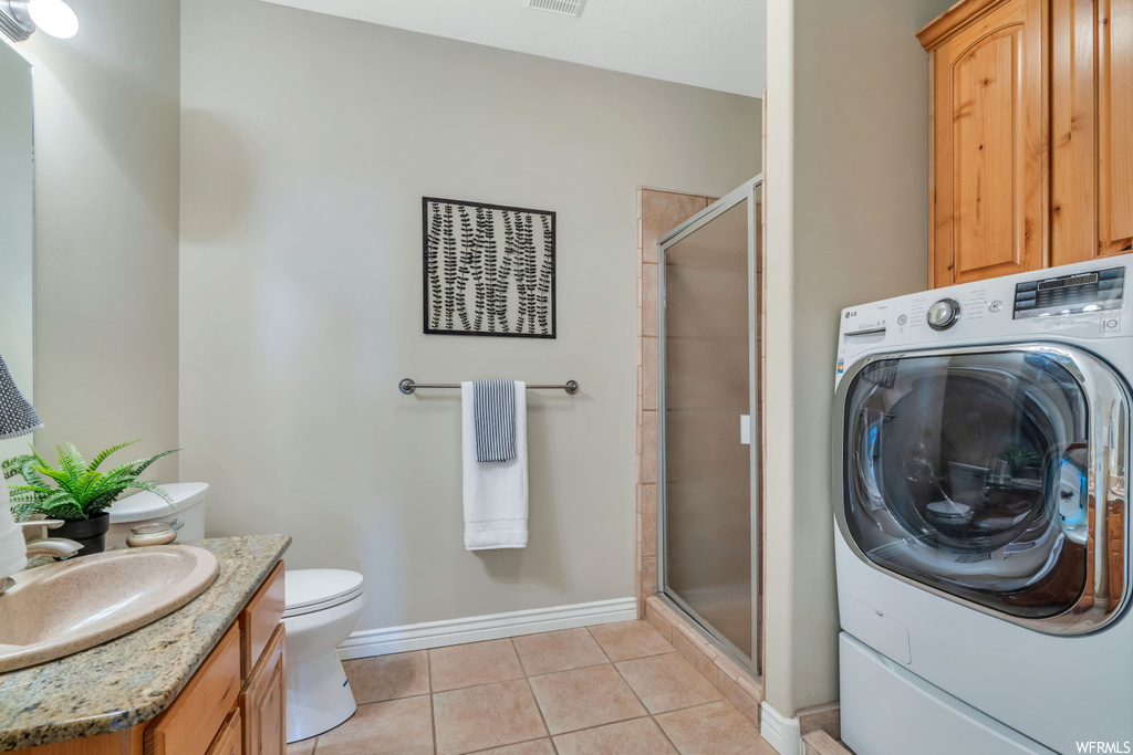 Interior space with washer / dryer, sink, and light tile floors