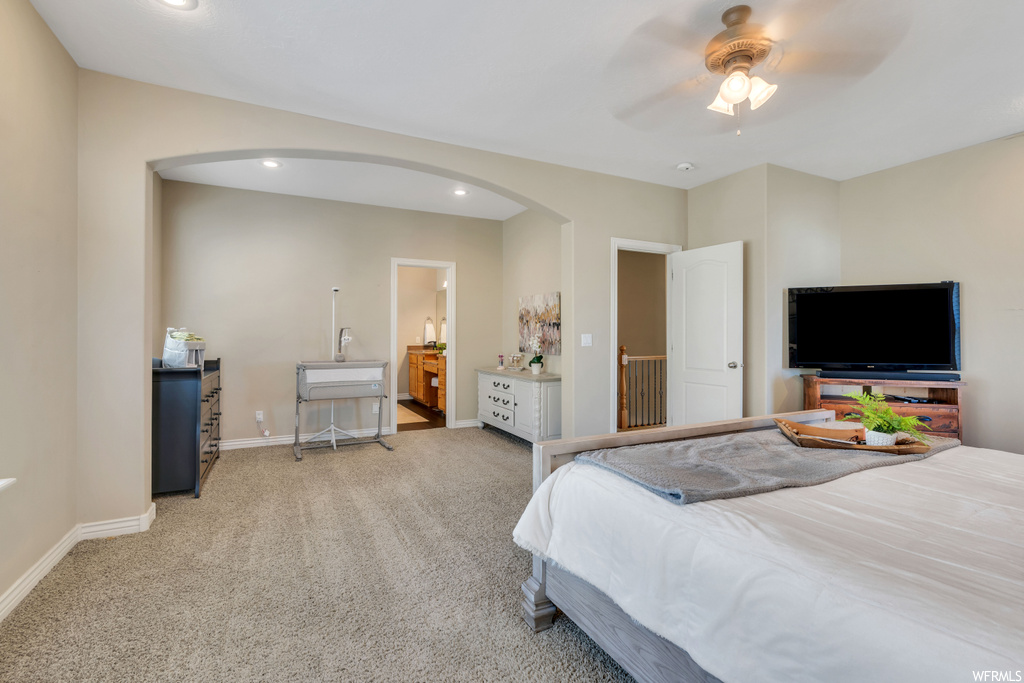 Bedroom with light colored carpet, ceiling fan, and ensuite bath