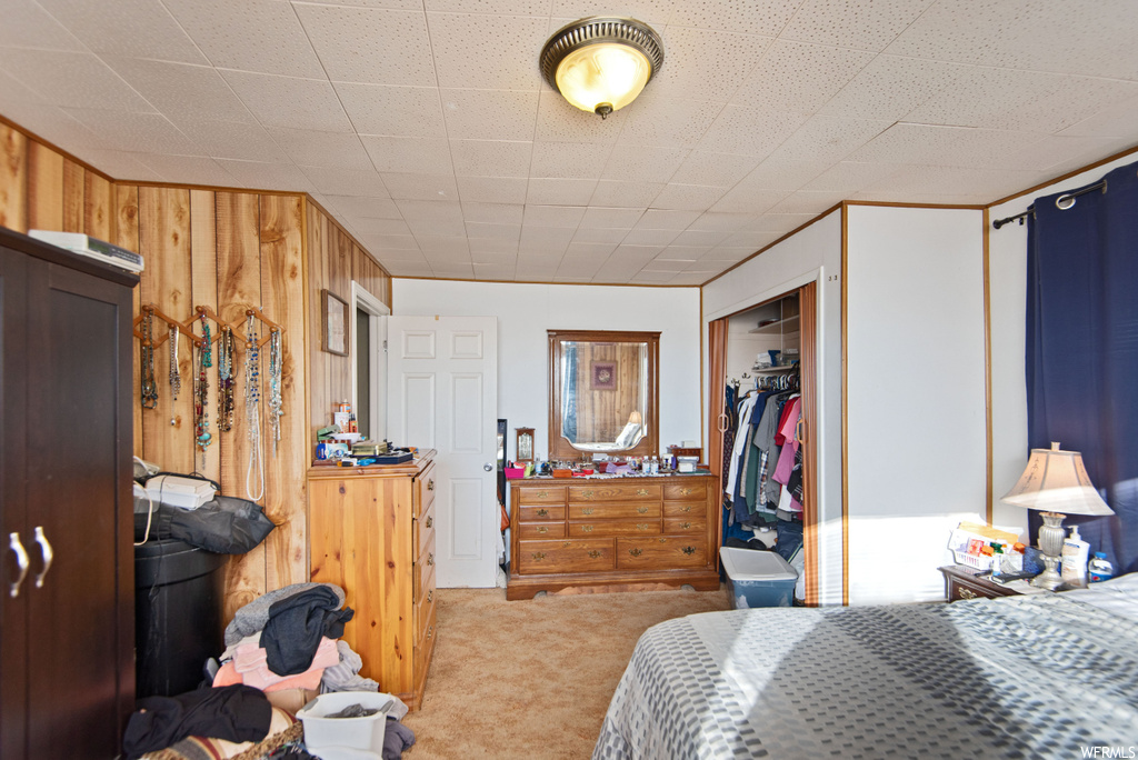 Bedroom featuring wood walls, a closet, and light carpet