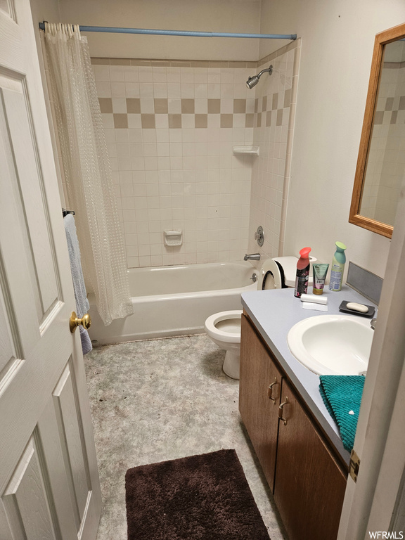 Full bathroom featuring toilet, vanity with extensive cabinet space, tile flooring, and shower / bath combo