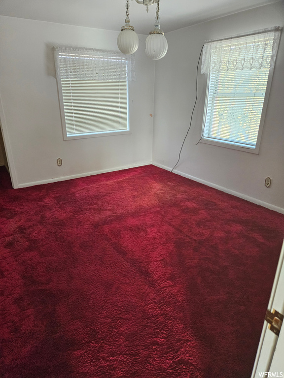 Carpeted spare room featuring an inviting chandelier