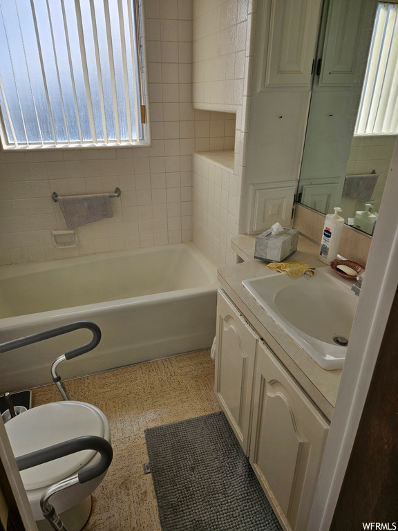 Bathroom featuring a healthy amount of sunlight, a washtub, and vanity