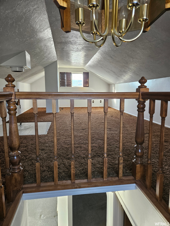Stairway featuring a notable chandelier, lofted ceiling, a textured ceiling, and carpet