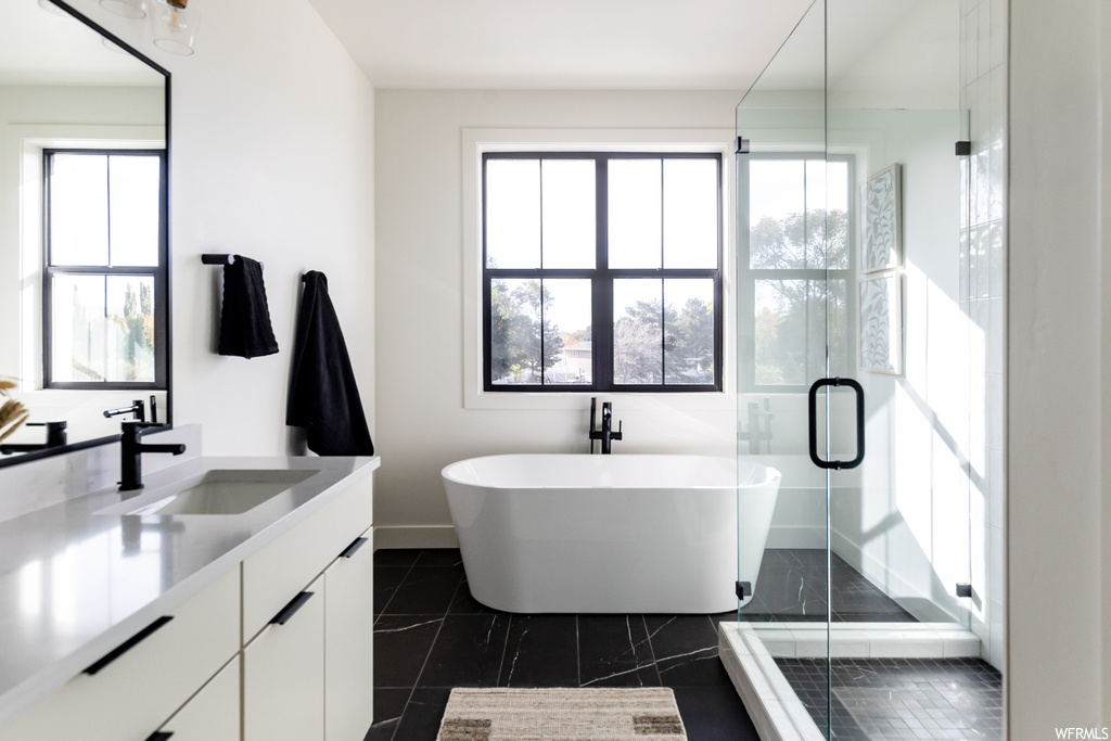 Bathroom featuring shower with separate bathtub, tile floors, and large vanity