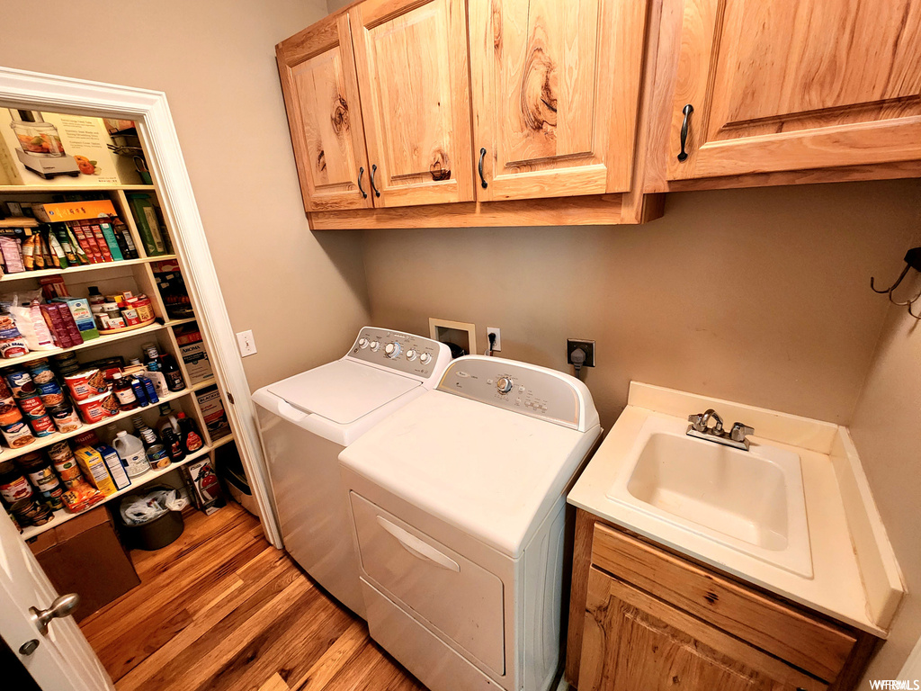 Laundry area with cabinets, hardwood / wood-style floors, sink, electric dryer hookup, and separate washer and dryer