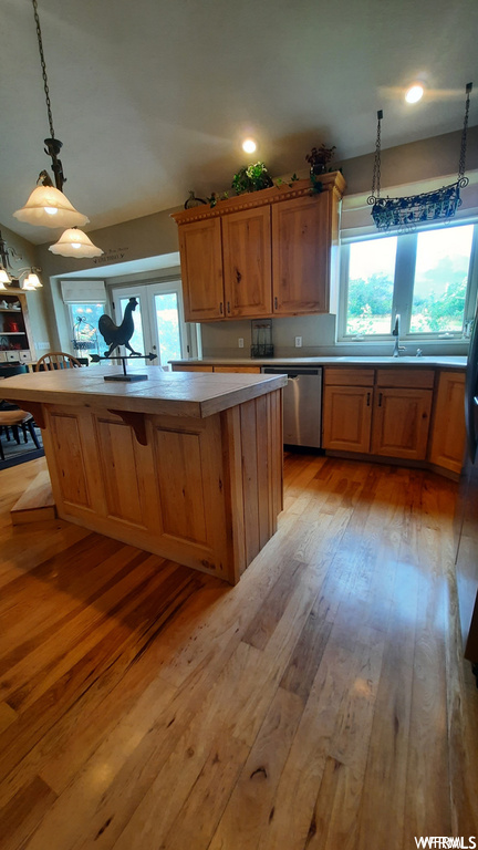 Kitchen featuring sink, dishwasher, pendant lighting, and light hardwood / wood-style flooring