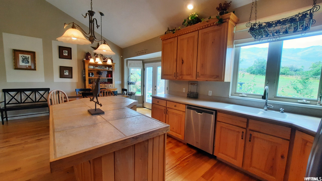 Kitchen with dishwasher, sink, lofted ceiling, decorative light fixtures, and light hardwood / wood-style flooring
