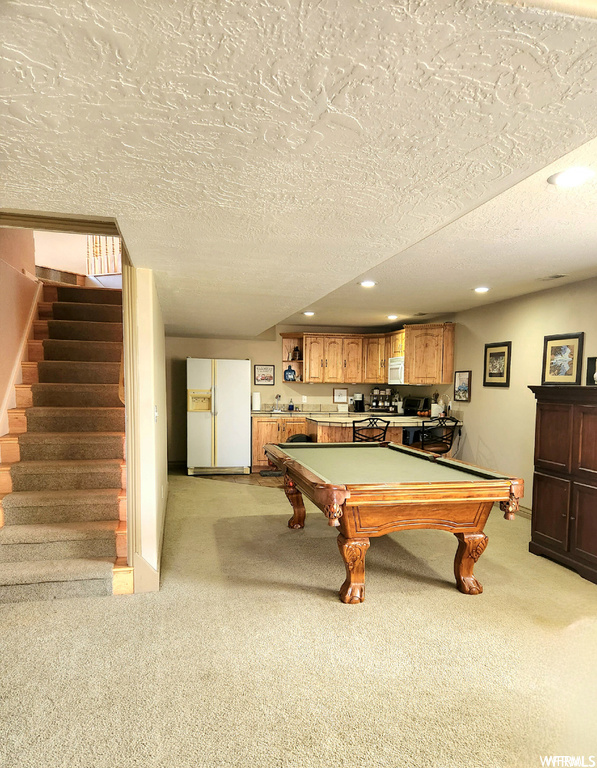 Rec room featuring pool table, a textured ceiling, and light carpet