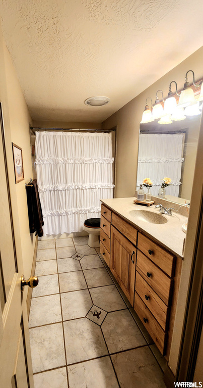 Bathroom with toilet, tile floors, and large vanity