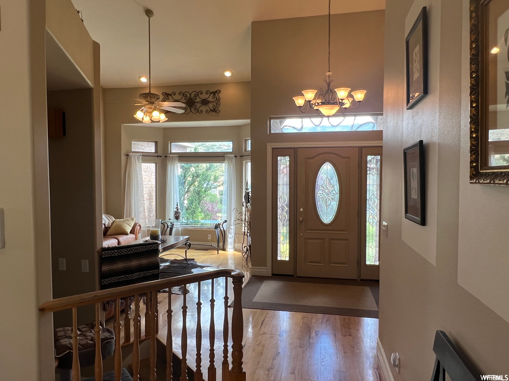 Entrance foyer featuring ceiling fan with notable chandelier and hardwood / wood-style flooring