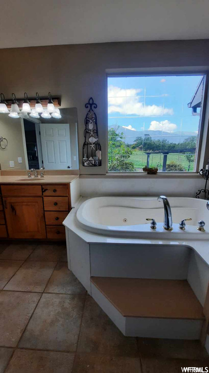 Bathroom with a tub, vanity, and tile floors