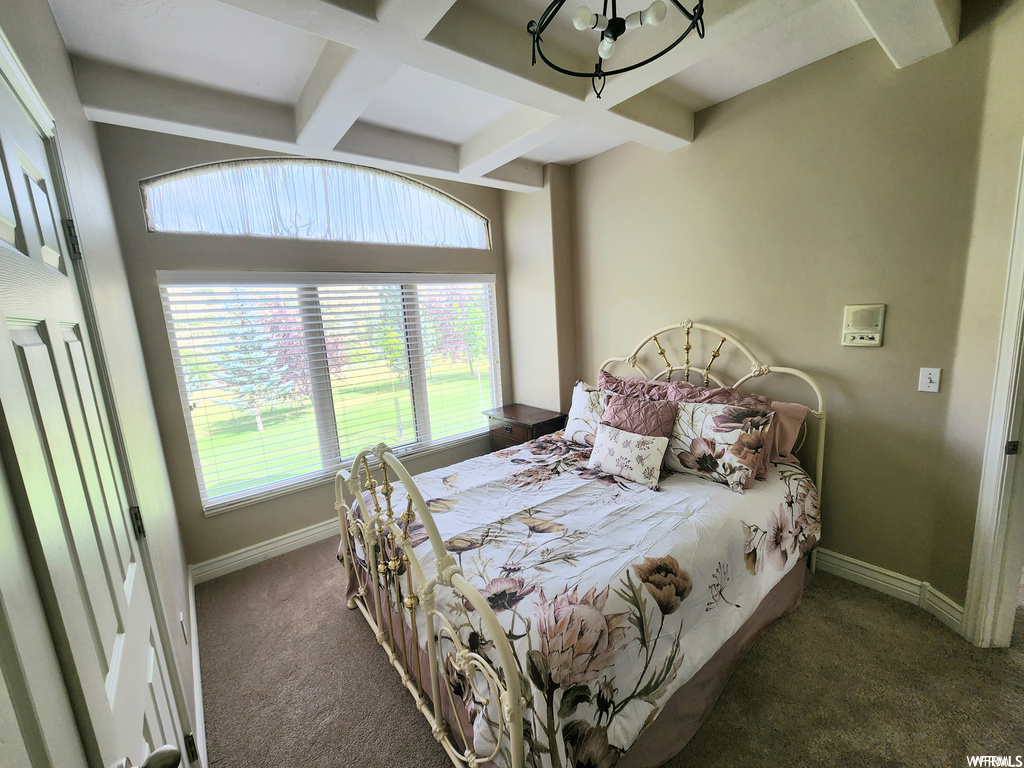 Carpeted bedroom with a chandelier, beam ceiling, and coffered ceiling