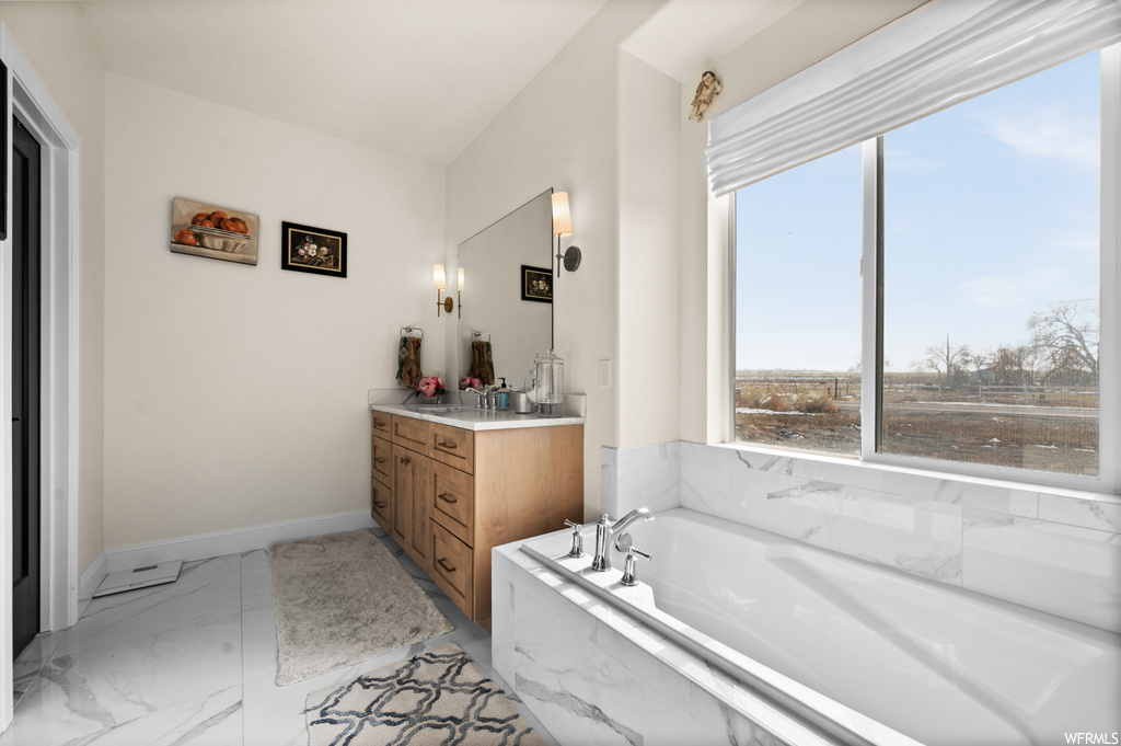 Bathroom featuring tiled bath, tile floors, and vanity