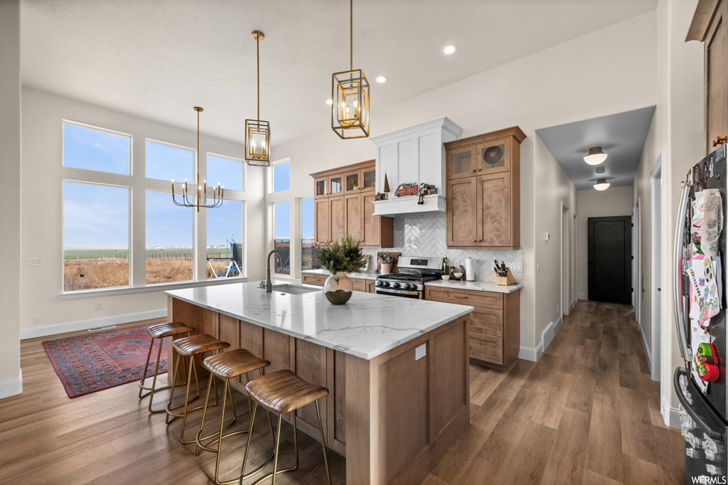Kitchen featuring tasteful backsplash, dark hardwood / wood-style floors, appliances with stainless steel finishes, and a kitchen island with sink