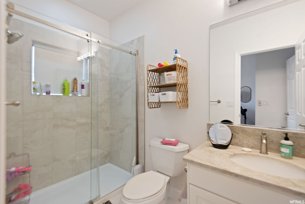 Bathroom featuring toilet, a shower with shower door, and vanity with extensive cabinet space