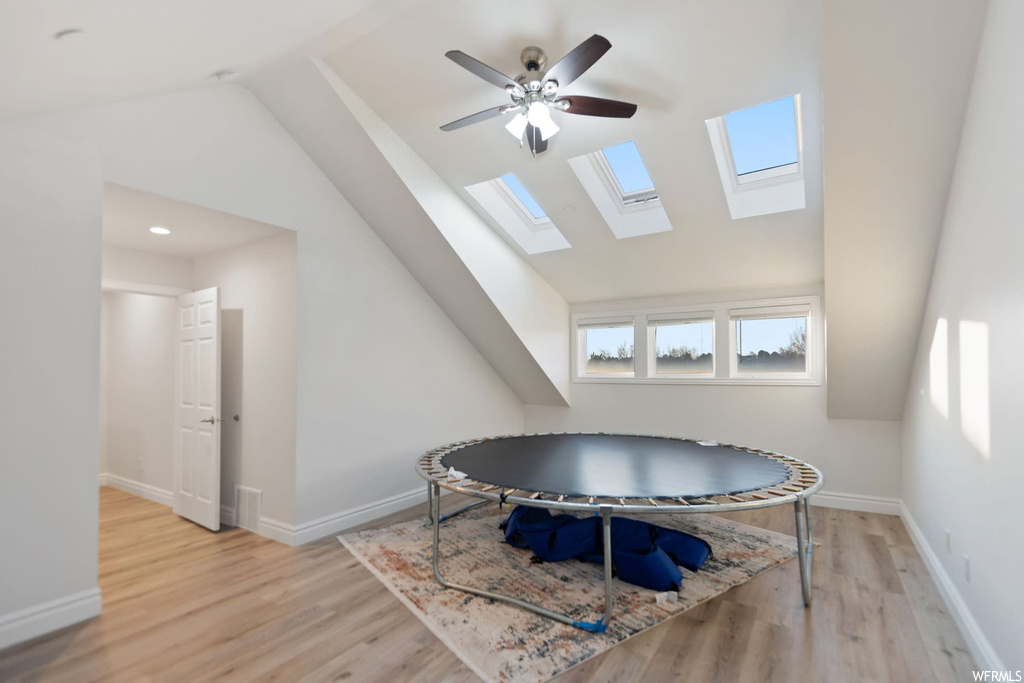 Dining area with ceiling fan, light hardwood / wood-style floors, and vaulted ceiling with skylight