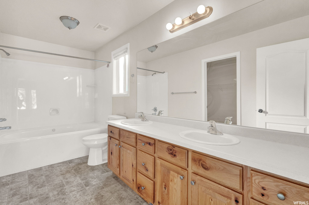 Full bathroom with tub / shower combination, dual sinks, large vanity, toilet, and tile floors