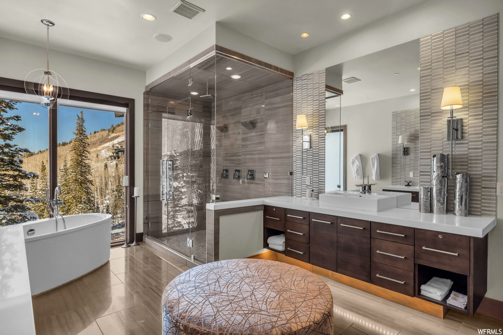 Bathroom featuring plenty of natural light, a chandelier, tile flooring, separate shower and tub, and oversized vanity