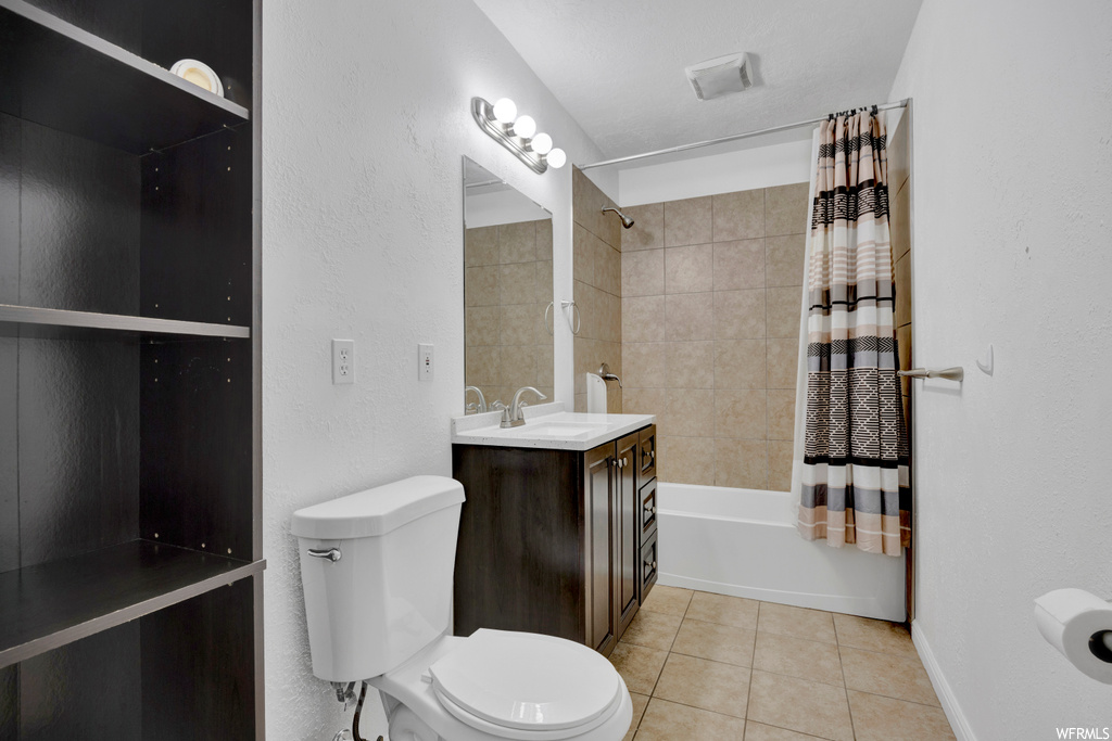 Full bathroom with toilet, shower / bath combo with shower curtain, tile floors, and vanity