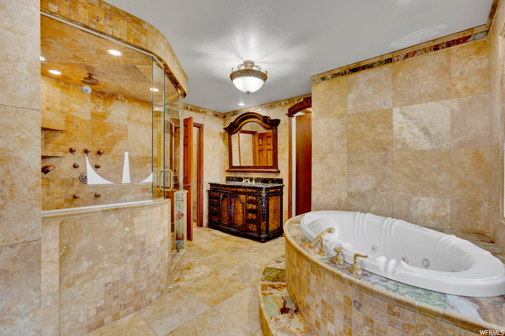 Bathroom featuring vanity, shower with separate bathtub, tile floors, and tile walls