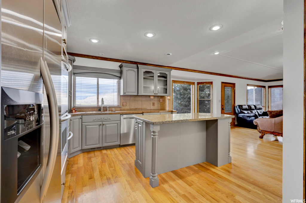 Kitchen featuring light wood-type flooring, a center island, stainless steel appliances, and crown molding
