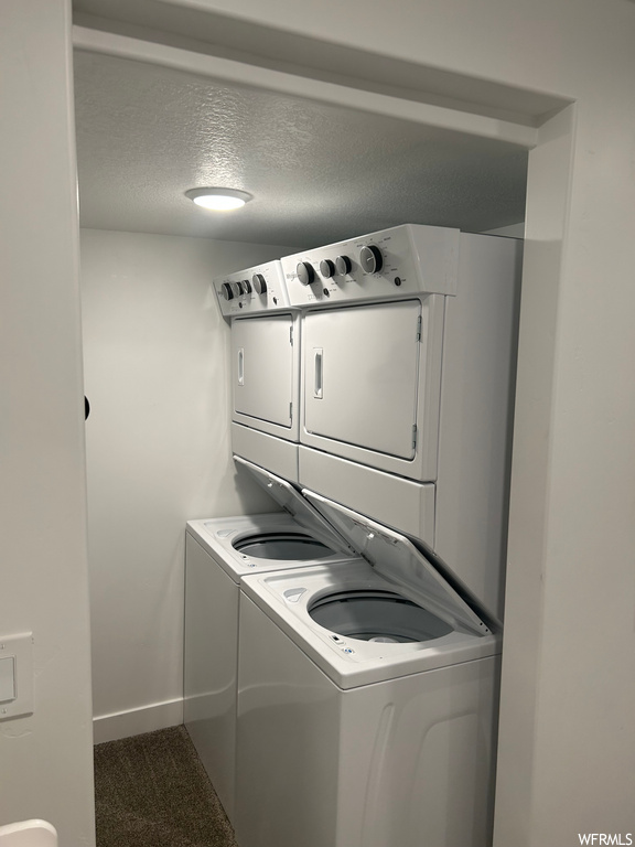 Laundry room featuring a textured ceiling and stacked washer / drying machine