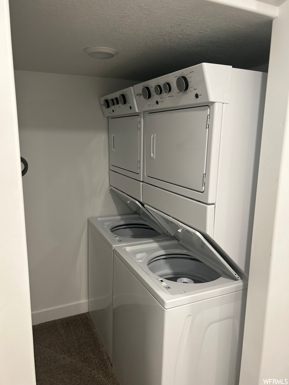 Washroom with dark colored carpet and stacked washer and dryer