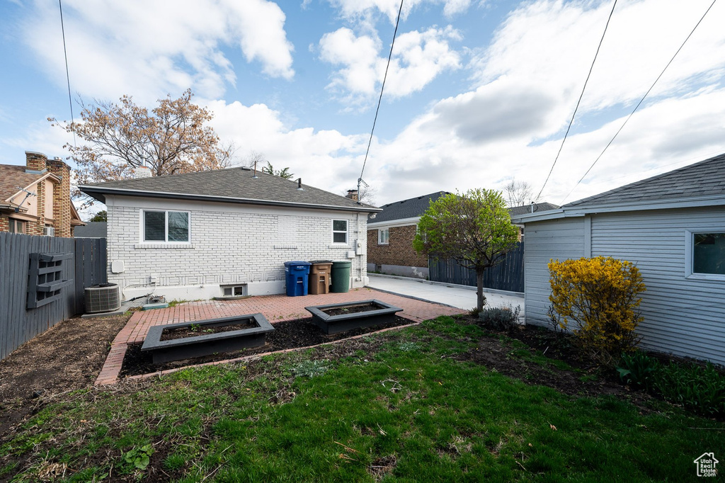Rear view of property featuring a wooden deck, central AC unit, a patio area, and a yard