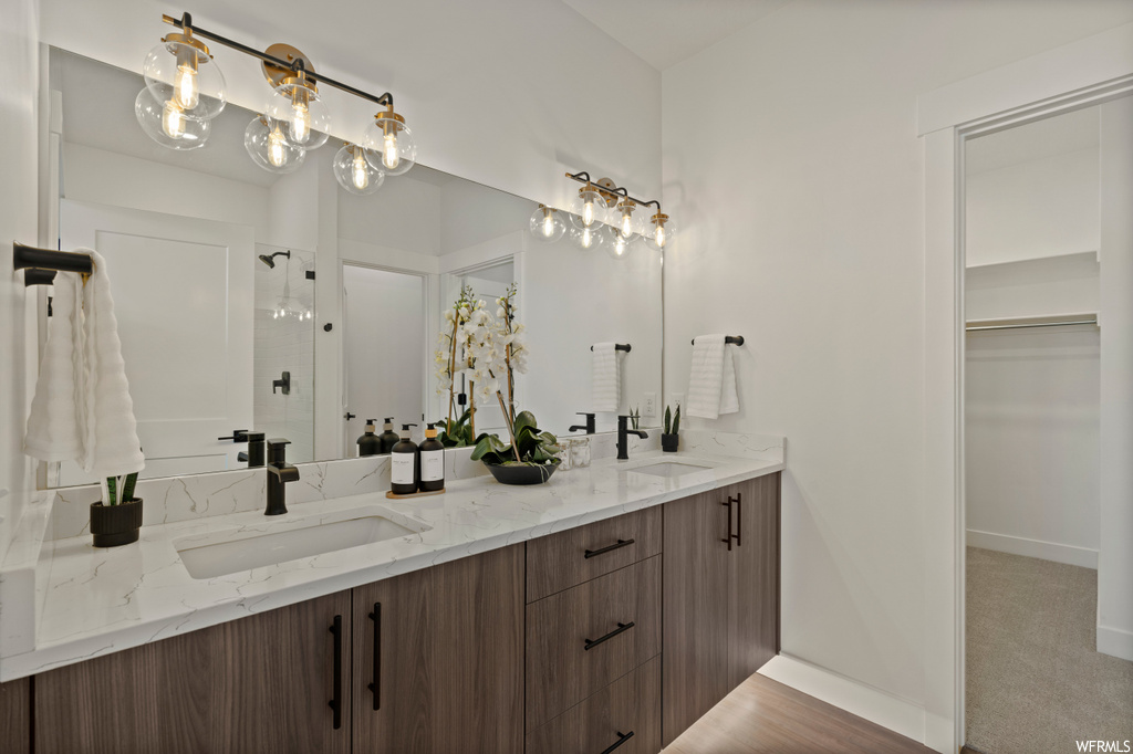 Bathroom with double sink, a chandelier, oversized vanity, and hardwood / wood-style flooring