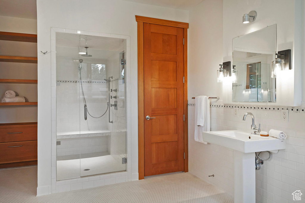 Bathroom featuring a shower with shower door, tile walls, tasteful backsplash, and tile floors