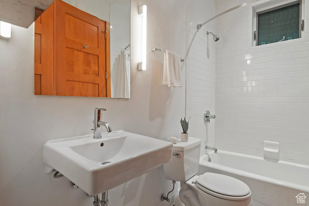 Full bathroom with sink, shower / bath combo with shower curtain, and toilet