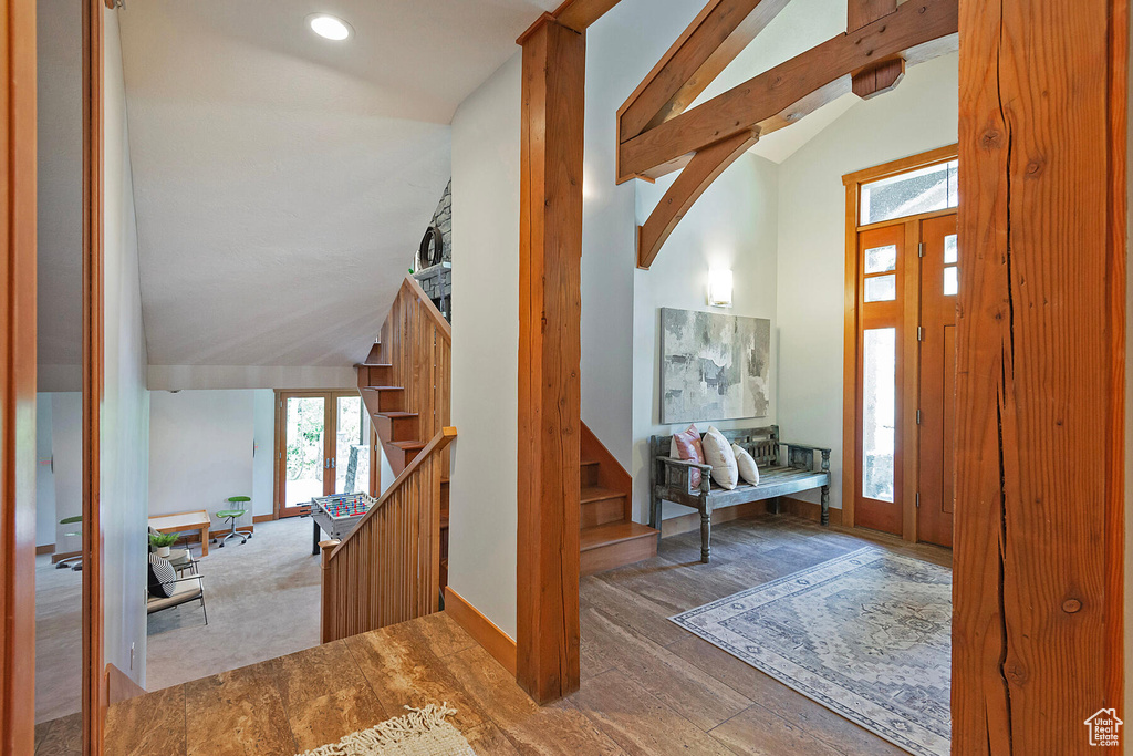 Carpeted entrance foyer with high vaulted ceiling and beam ceiling