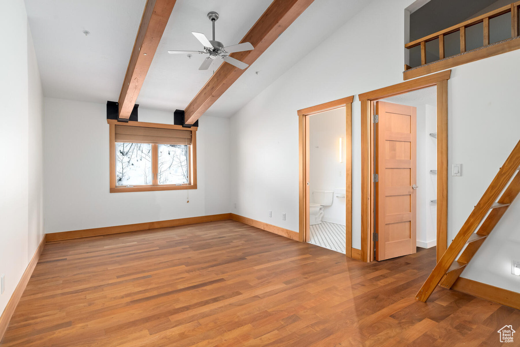 Empty room featuring wood-type flooring, vaulted ceiling with beams, and ceiling fan