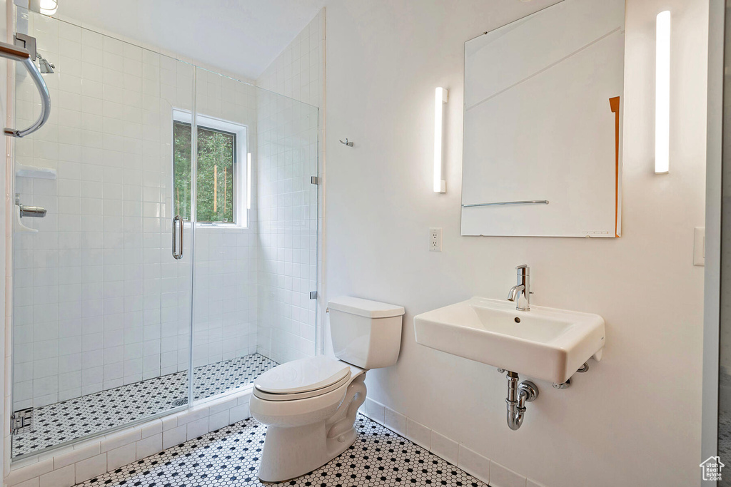 Bathroom with a shower with shower door, sink, tile flooring, and toilet