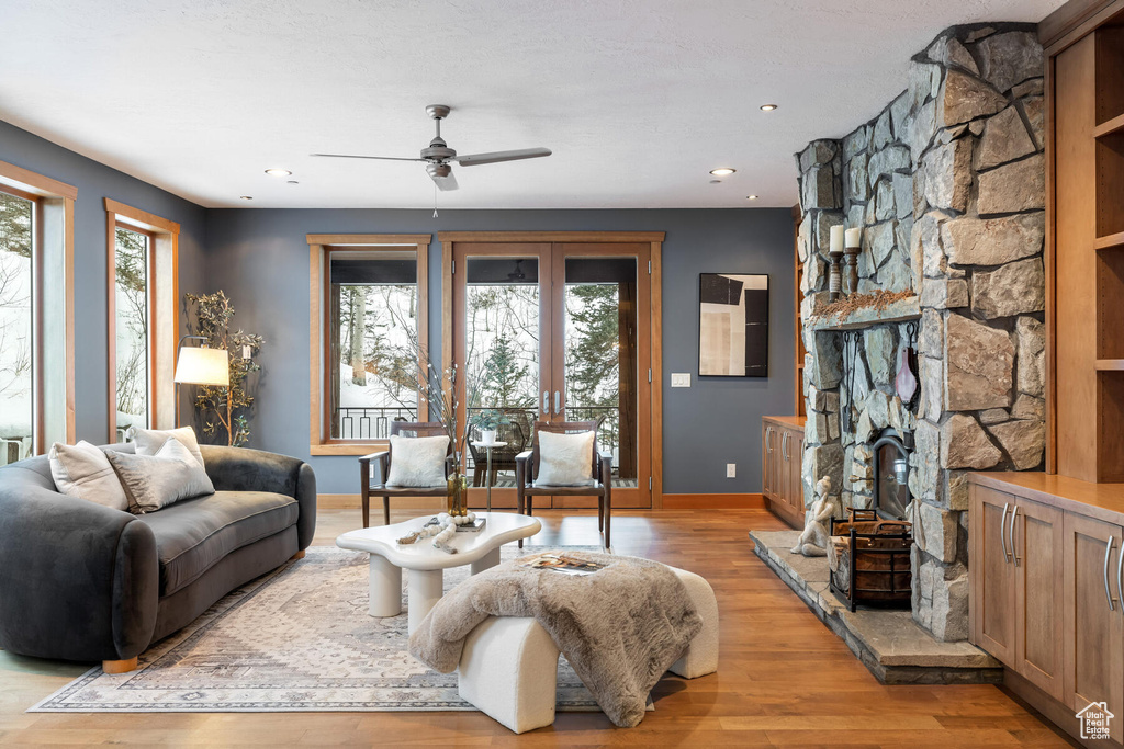 Living room featuring a fireplace, plenty of natural light, light wood-type flooring, and ceiling fan