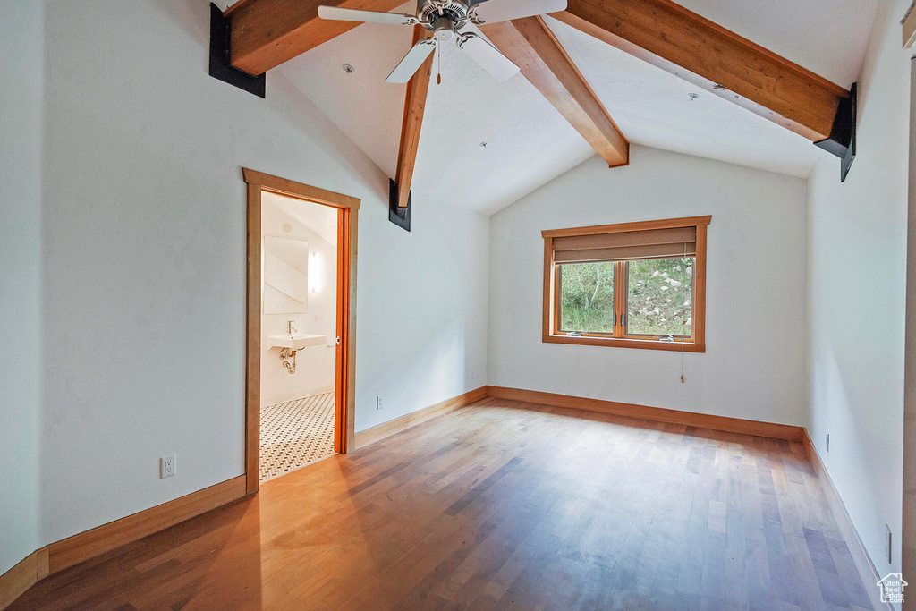 Empty room with hardwood / wood-style flooring, lofted ceiling with beams, and ceiling fan