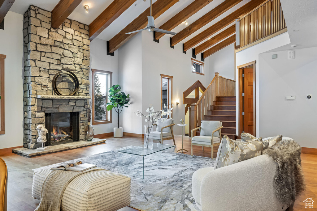 Living room with a stone fireplace, high vaulted ceiling, wood-type flooring, and ceiling fan