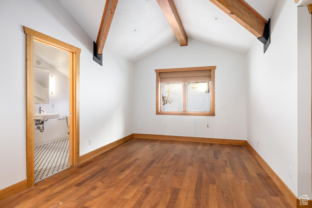 Unfurnished room with lofted ceiling with beams, hardwood / wood-style flooring, and sink