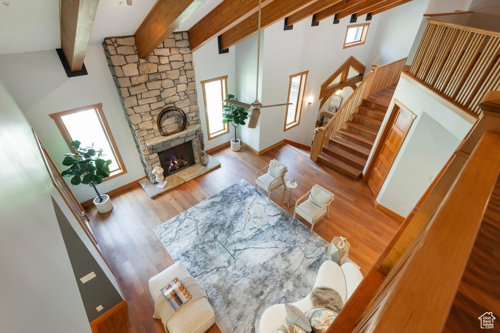 Living room with a fireplace, ceiling fan, beam ceiling, high vaulted ceiling, and wood-type flooring