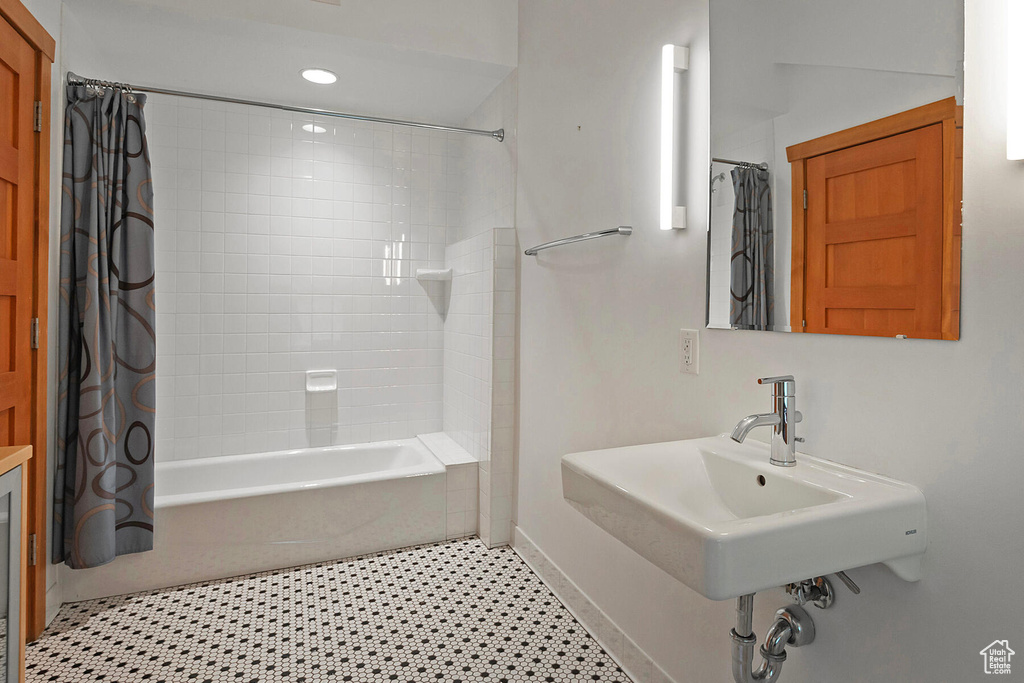 Bathroom with tile floors, sink, and shower / bath combo with shower curtain