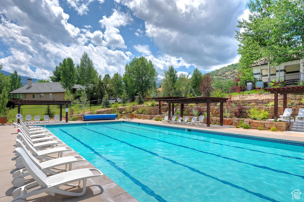 View of pool with a pergola and a patio