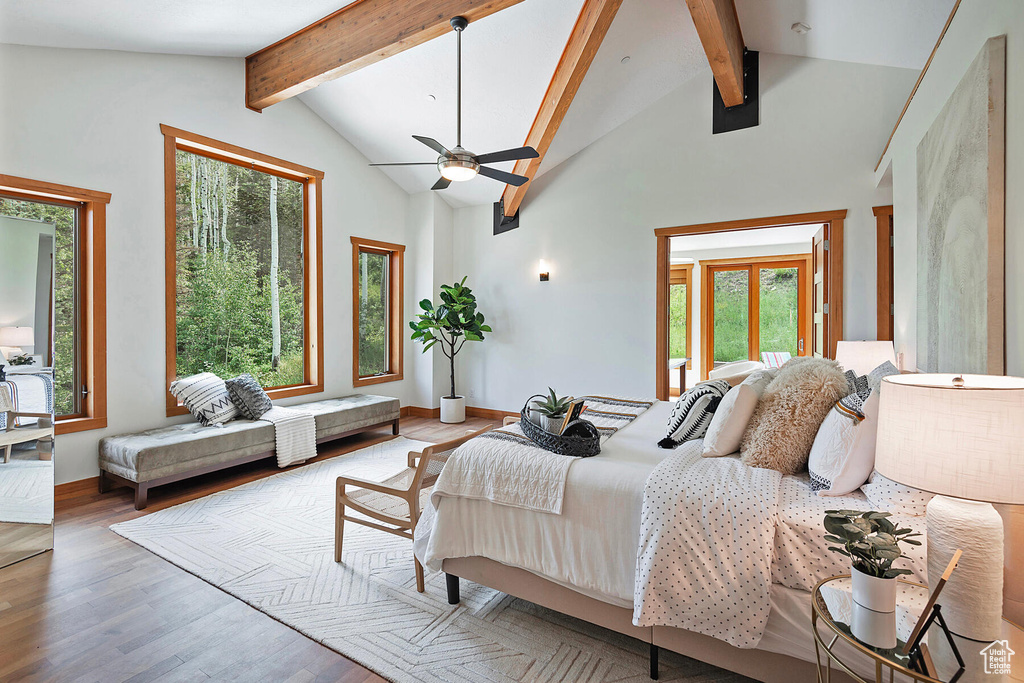 Bedroom featuring beamed ceiling, hardwood / wood-style floors, ceiling fan, and multiple windows