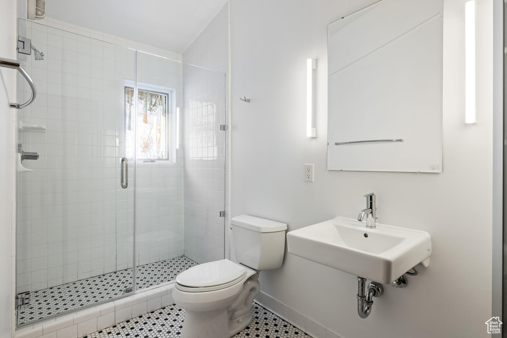 Bathroom with a shower with shower door, tile flooring, sink, and toilet