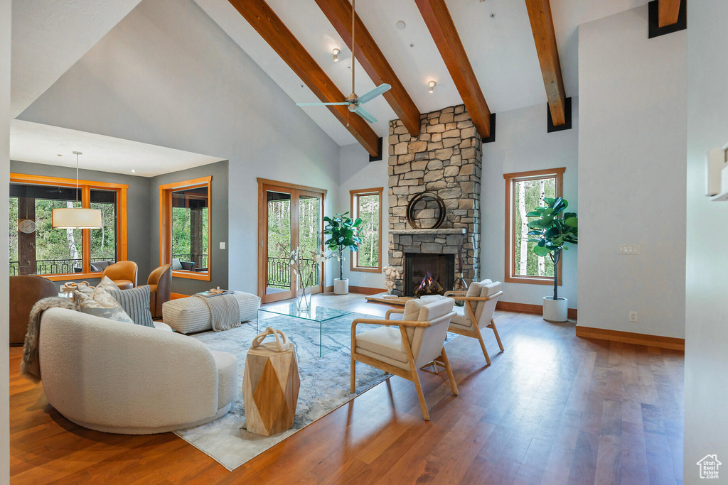 Living room featuring a stone fireplace, ceiling fan, plenty of natural light, and hardwood / wood-style floors